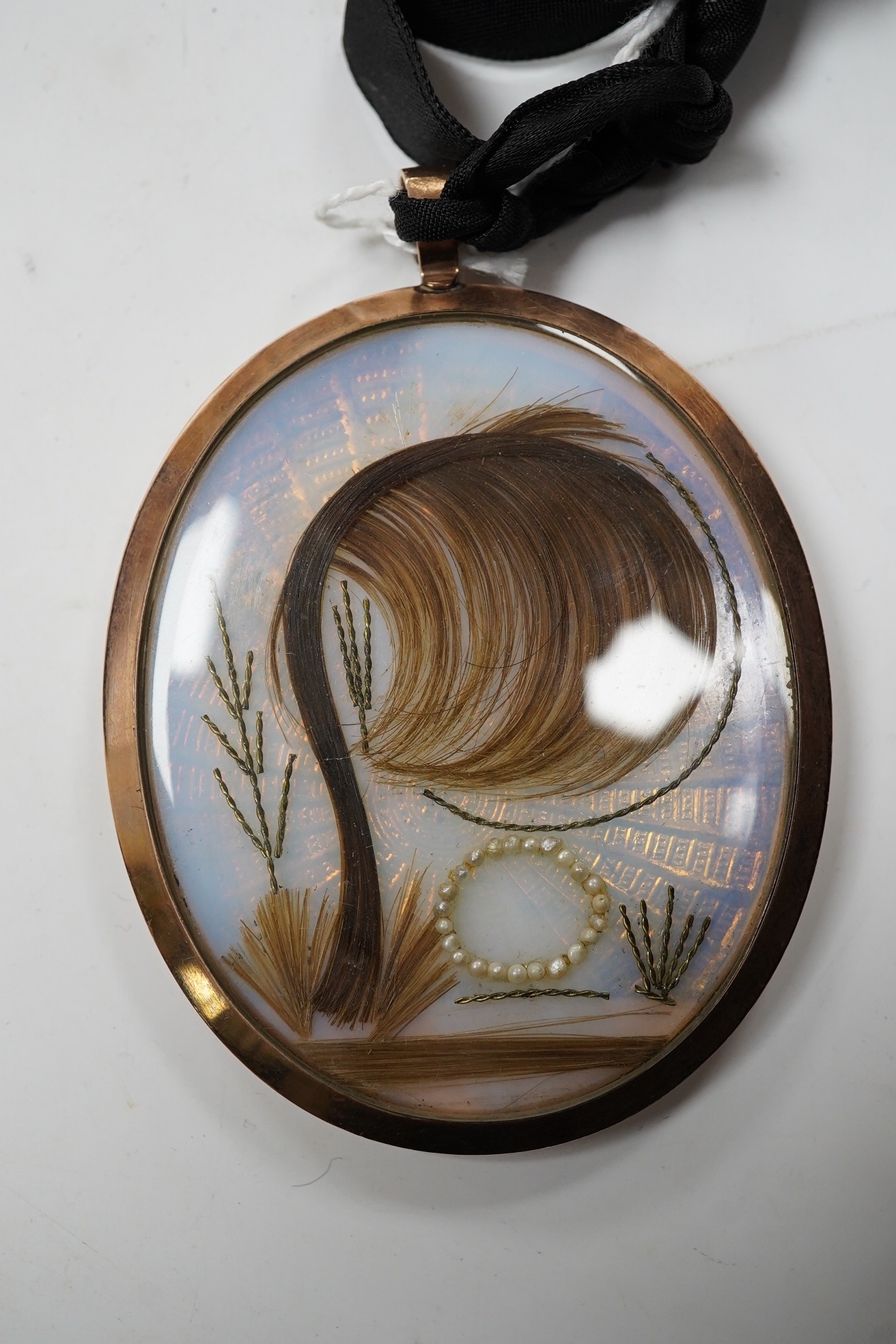 A late 18th century miniature on ivory, Portrait of a lady, initialled NR and dated 1799, lock of hair and seed pearls verso, housed in a yellow metal pendant case, overall 8.2cm x 5.9cm. CITES Submission reference DZHTZ